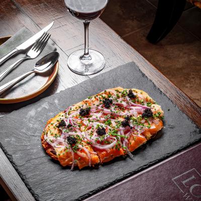 Flatbread topped with cheese vegetables and herbs.