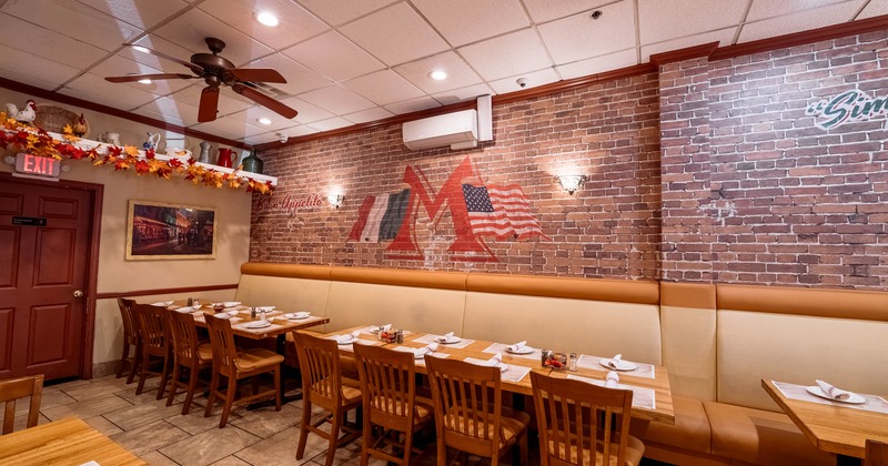 Interior of a restaurant with brick walls, wooden tables, and autumn decorations