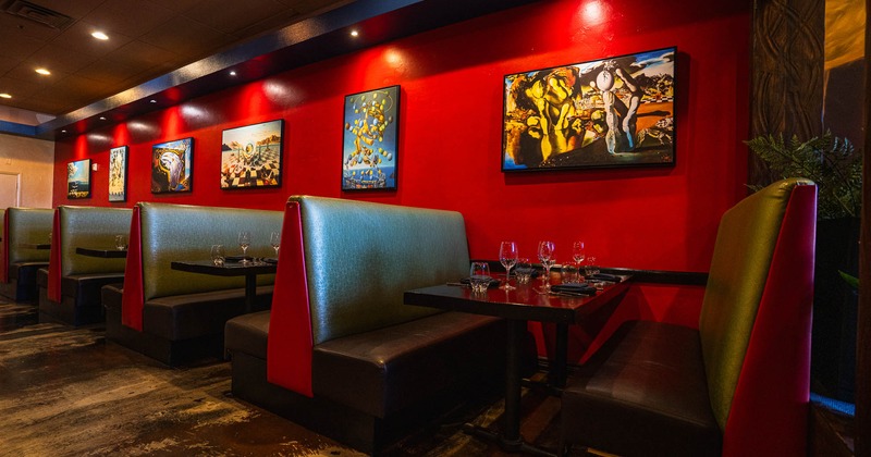 A restaurant interior with red walls, green booths, and surreal paintings
