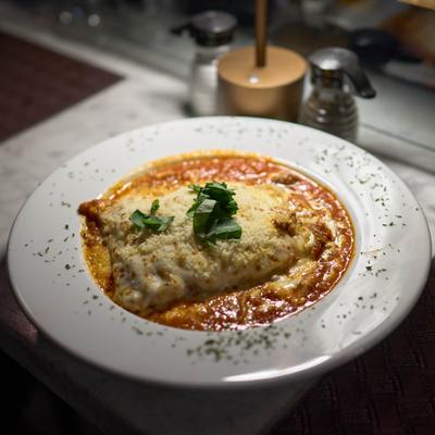 Baked lasagna topped with grated cheese and fresh basil herbs.
