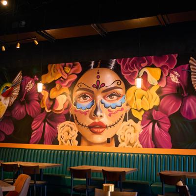 Colorful Day of the Dead-inspired wall mural above banquette seating.