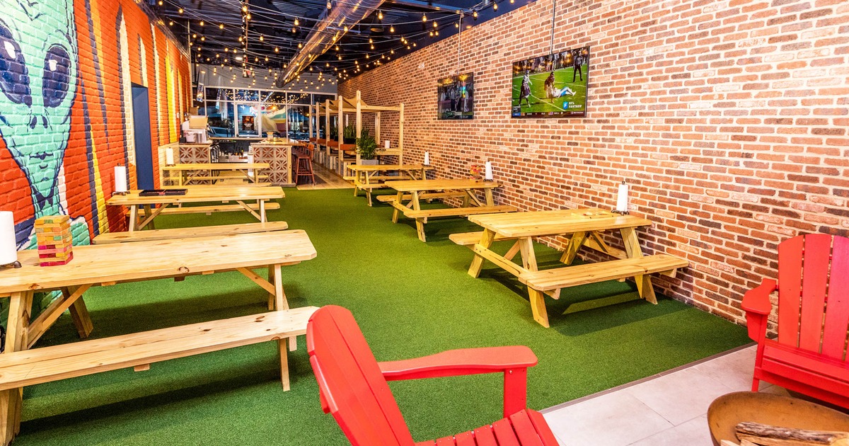 Interior, wooden tables with benches, alien mural, artificial grass floor, red brick wall