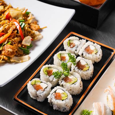 Sushi rolls on a table next to chicken soba noodles.