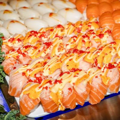 Assortment of salmon nigiri topped with a creamy sauce and garnishes.
