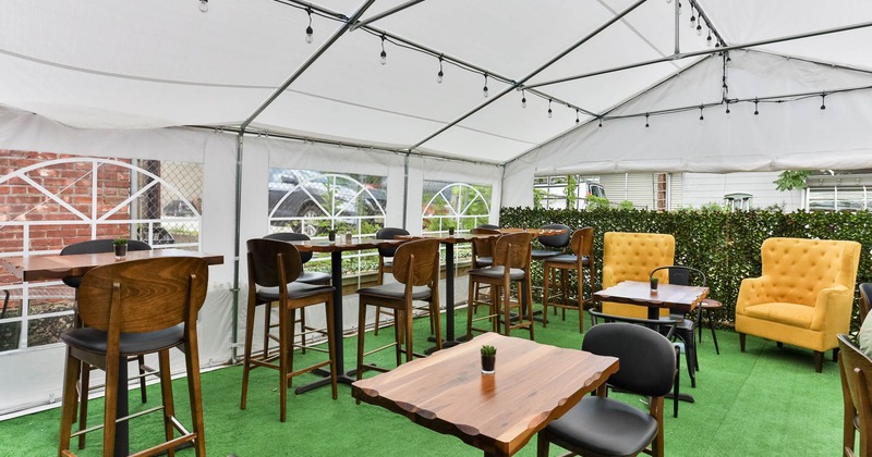 Exterior, patio under large white tent, seating area, high and regular seating, lanterns