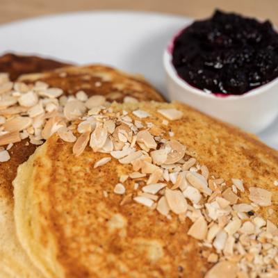 Buttermilk pancakes topped with almonds, served with a side of blueberry jam.