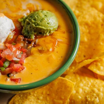Cheese dip topped with guacamole and sour cream, served with tortilla chips