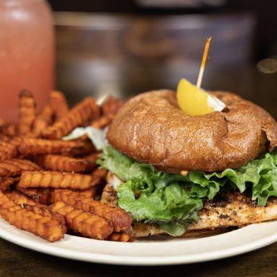 Mahi Sandwich with lettuce and a wegde of lemon, served with sweet potato fries.