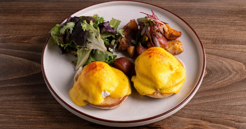 Eggs Benedict served with potatoes and greens