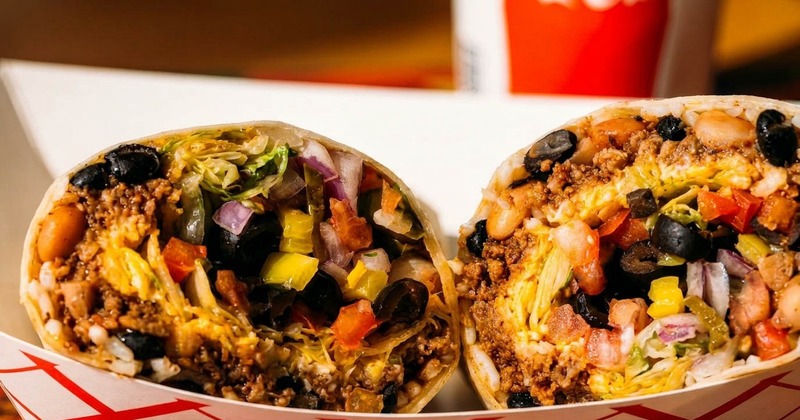 A burrito cut in half reveals meat, rice, and vegetables