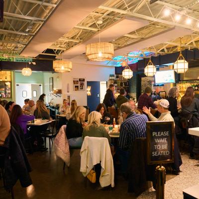 Dining area with overhead lightning and people seated at tables.