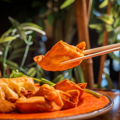 Fried wonton held with chopsticks.