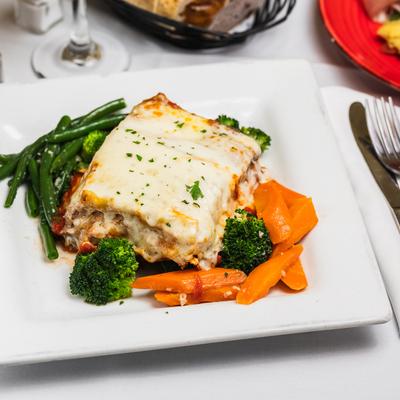 Lasagna served with cooked veggies on a plate.