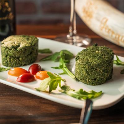 Pkhali featuring shaped, savory spinach and walnut mixtures served with garnishes.