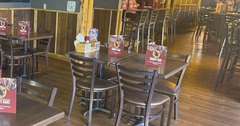 Dining area with tables, chairs, TV screen on the wall and string lights