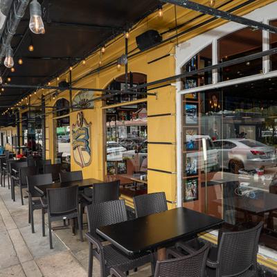 Outdoor seating with string lights and reflective windows.