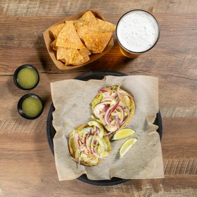 plate with 2 tostadas, a beer, chips and salsa.