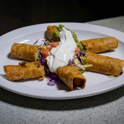 Flautas topped with sour cream and guacamole.