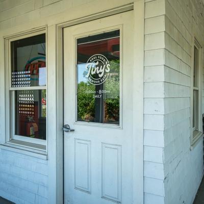 Restaurant entrance with white wooden facade and doors with a sign.