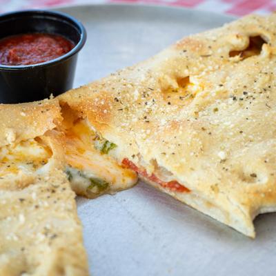 A halved calzone and marinara sauce, close-up.