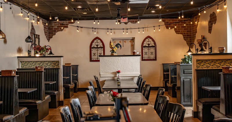 Interior seating area with black booths, chairs and wooden tables
