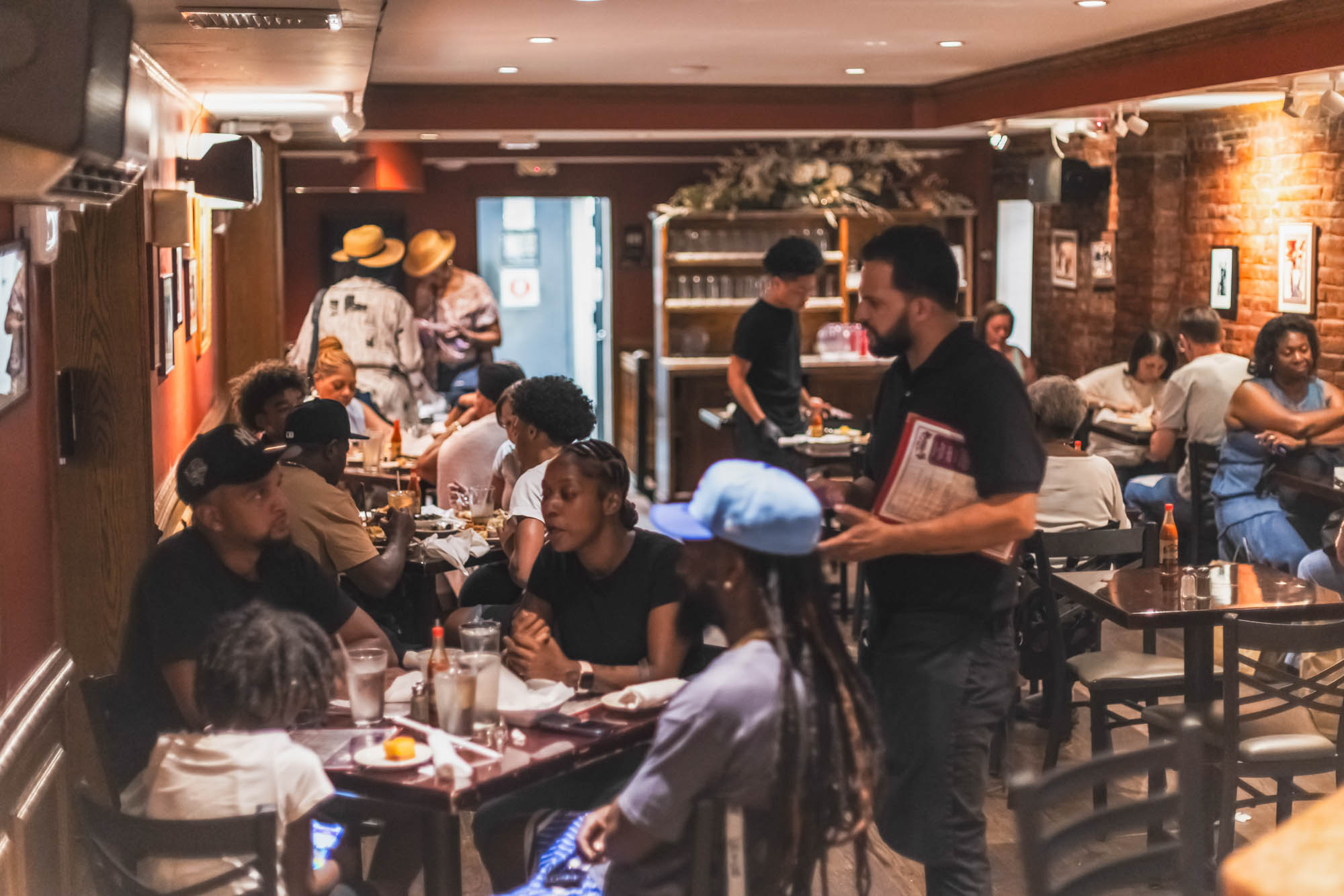 Patrons in the dining room being served by a server