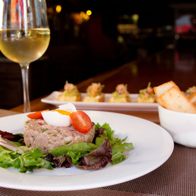 Tartare steak with a raw egg yolk, mixed greens, toast, and wine.