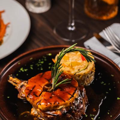 Pork Chop topped with grilled pineapple, served with rice and garnsihed with rosemary.