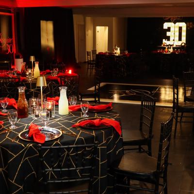 Elegant black and gold patterned tablecloths with vibrant red napkins for a thirtieth birthday.