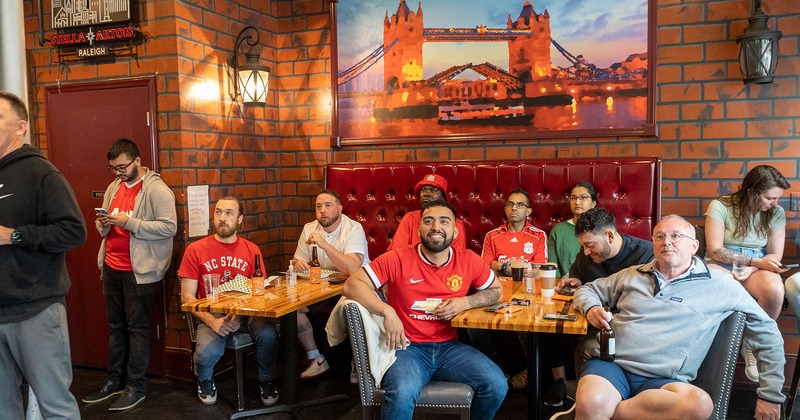 Interior, guests enjoying drinks and watching a soccer match on TV