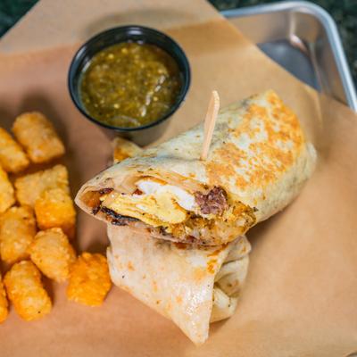 Breakfast burrito, with tater tots and green salsa.