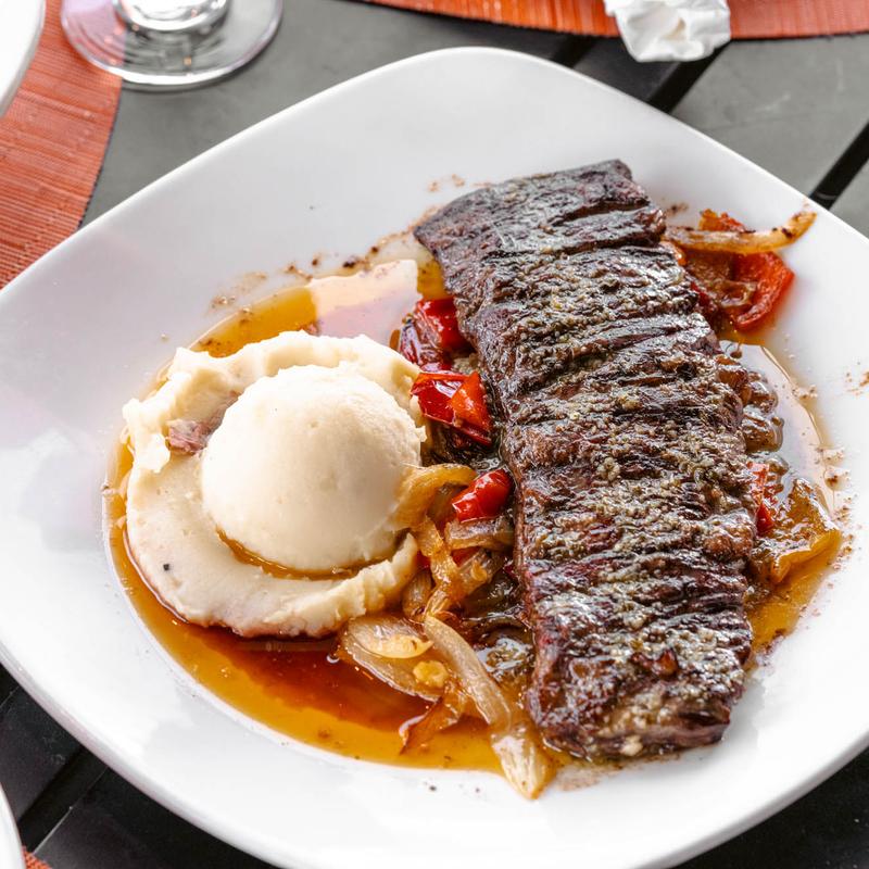 Grilled steak served alongside mashed potatoes and peppers