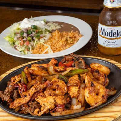 Chicken, steak, and shrimp Fajitas, with grilled onions and bell peppers.