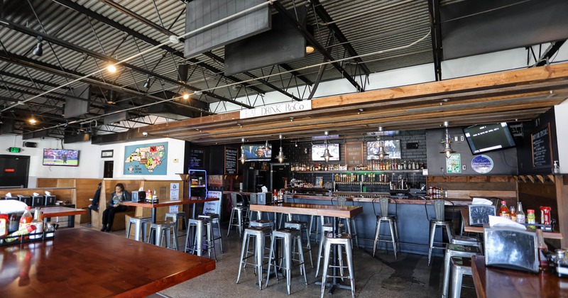 Interior, high seating area, high tables with metal stools, bar in the back