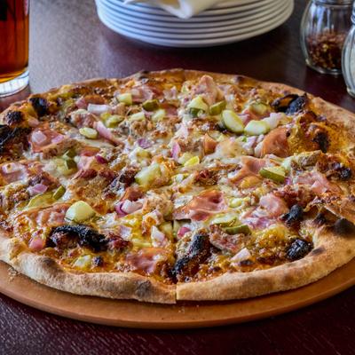 Cuban pizza topped with ham, pickles and onions.