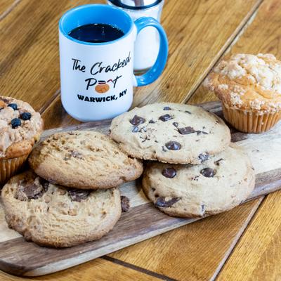 Cookies and muffins servd on a wooden board alongside a coffee mug.