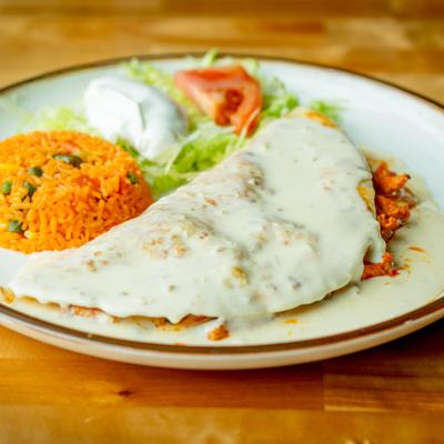 Chicken Quesadilla smothered in cheese sauce, served with rice, sour cream, and tomato.