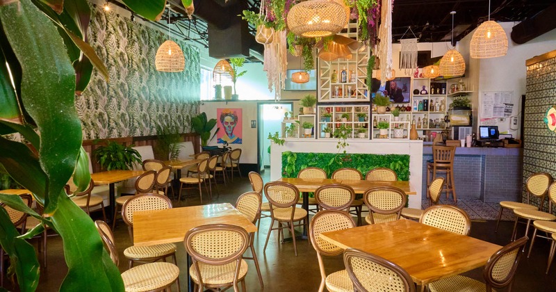 Interior, dining area, wooden top tables with chairs, lavish plant decoration