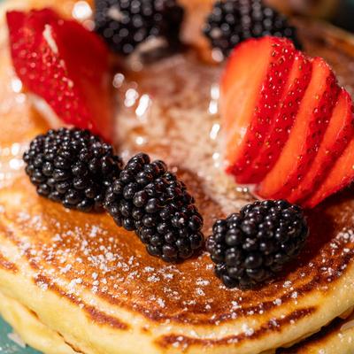 Close up of pancakes topped with honey butter and fresh berries.