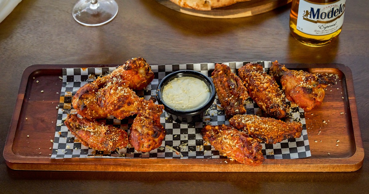 Seasoned chicken wings with dipping sauce on a tray