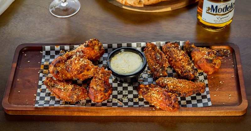 Seasoned chicken wings with dipping sauce on a tray