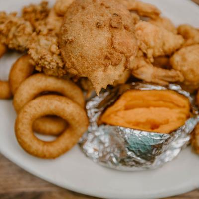 Fried seafood served with onion rings, fried pickles and baked sweet potato.