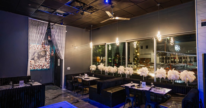 Interior of a modern dining area with dark decor, large windows, and feather decorations