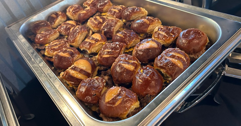 A large tray of pretzel bun sliders