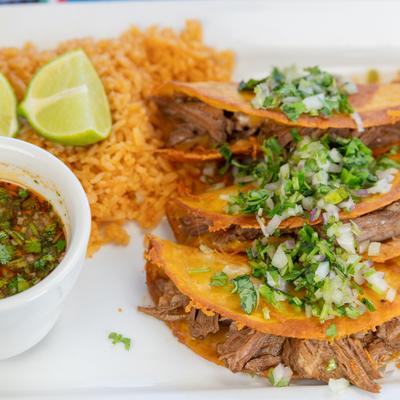 Quesabirria tacos with rice and dipping broth.
