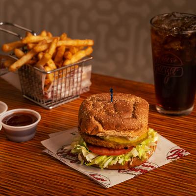 Veggie burger with fries, dipping sauce, and a glass of soda.