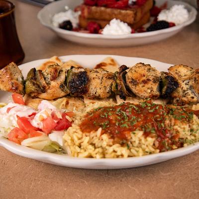 Chicken skewers with seasoned rice, pita bread, and salad.