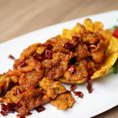 Dry pepper chicken with garnish on a white plate.
