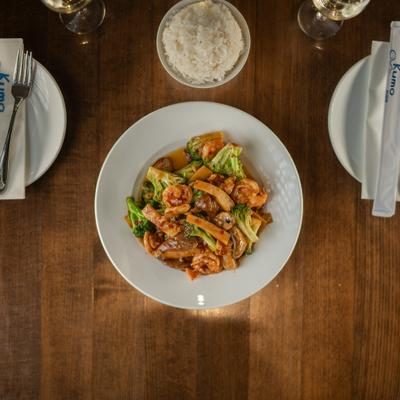 Shrimp and vegetable stir fry with rice on a restaurant table.