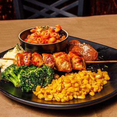 A plate of corn, chicken skewers, broccoli, and pasta.
